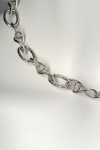Detail of sculptural DNA double helix link in sterling silver, symbolising invisible human connection.