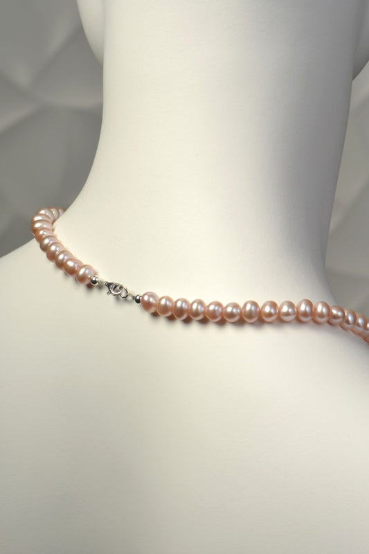 clasp detail on pink cultured pearl necklace on a mannequin with a plain background