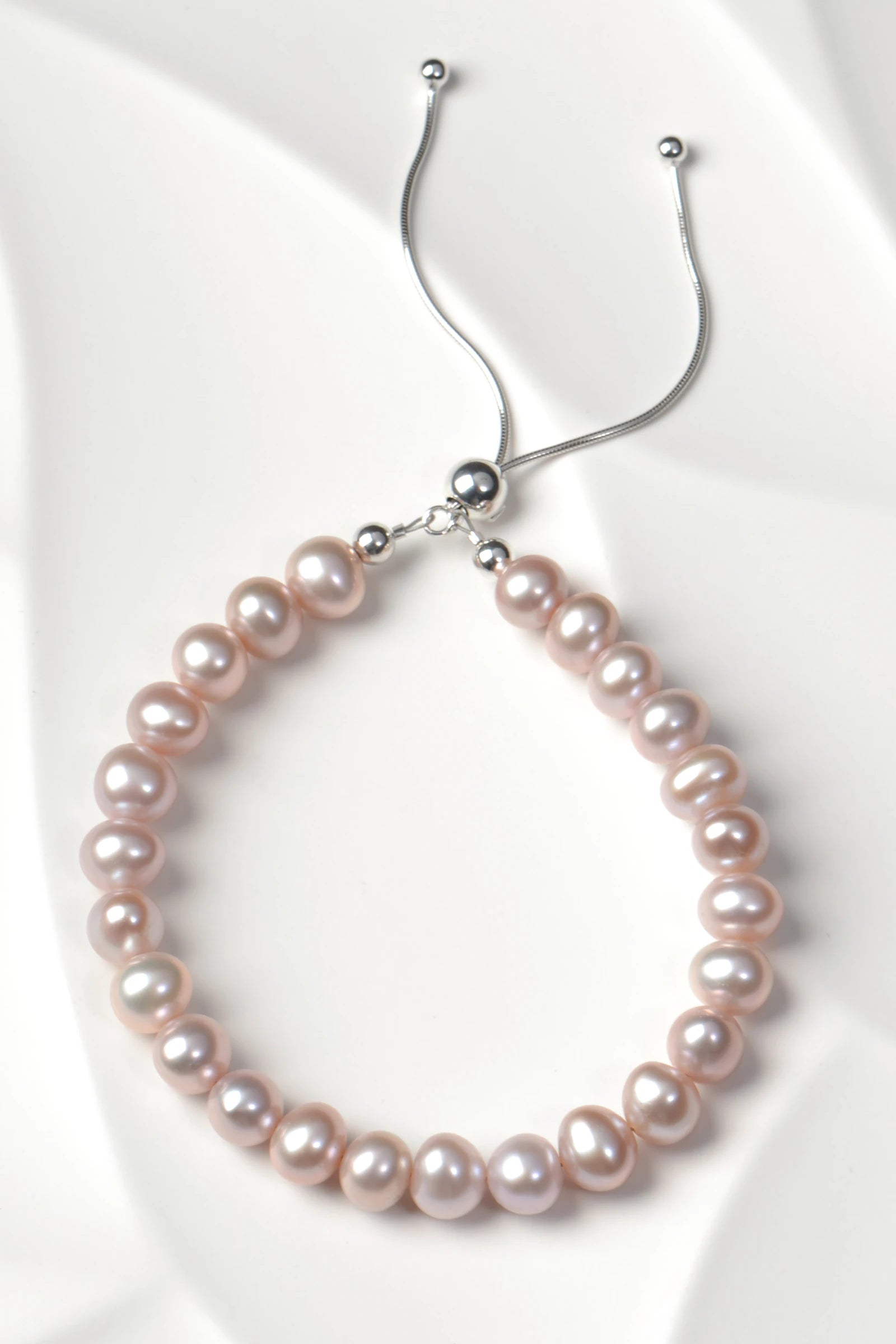 Real cultured pearl bracelet in pale pink with a sterling silver clasp on a white textured tile - Christine SSadler