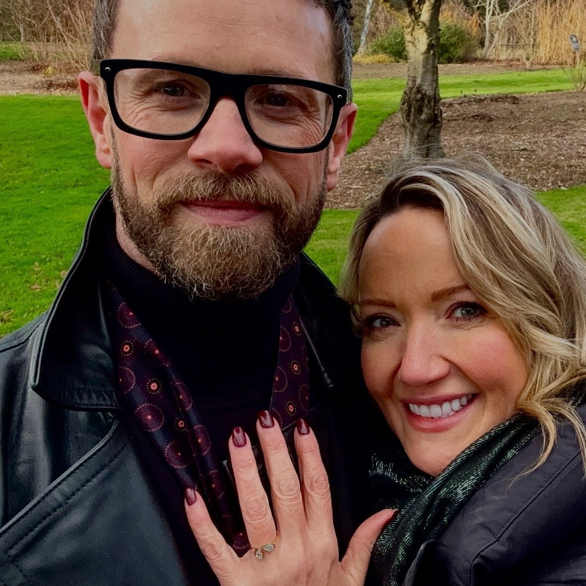 Man and woman standing outdoors with a Christine Sadler engagement ring on display