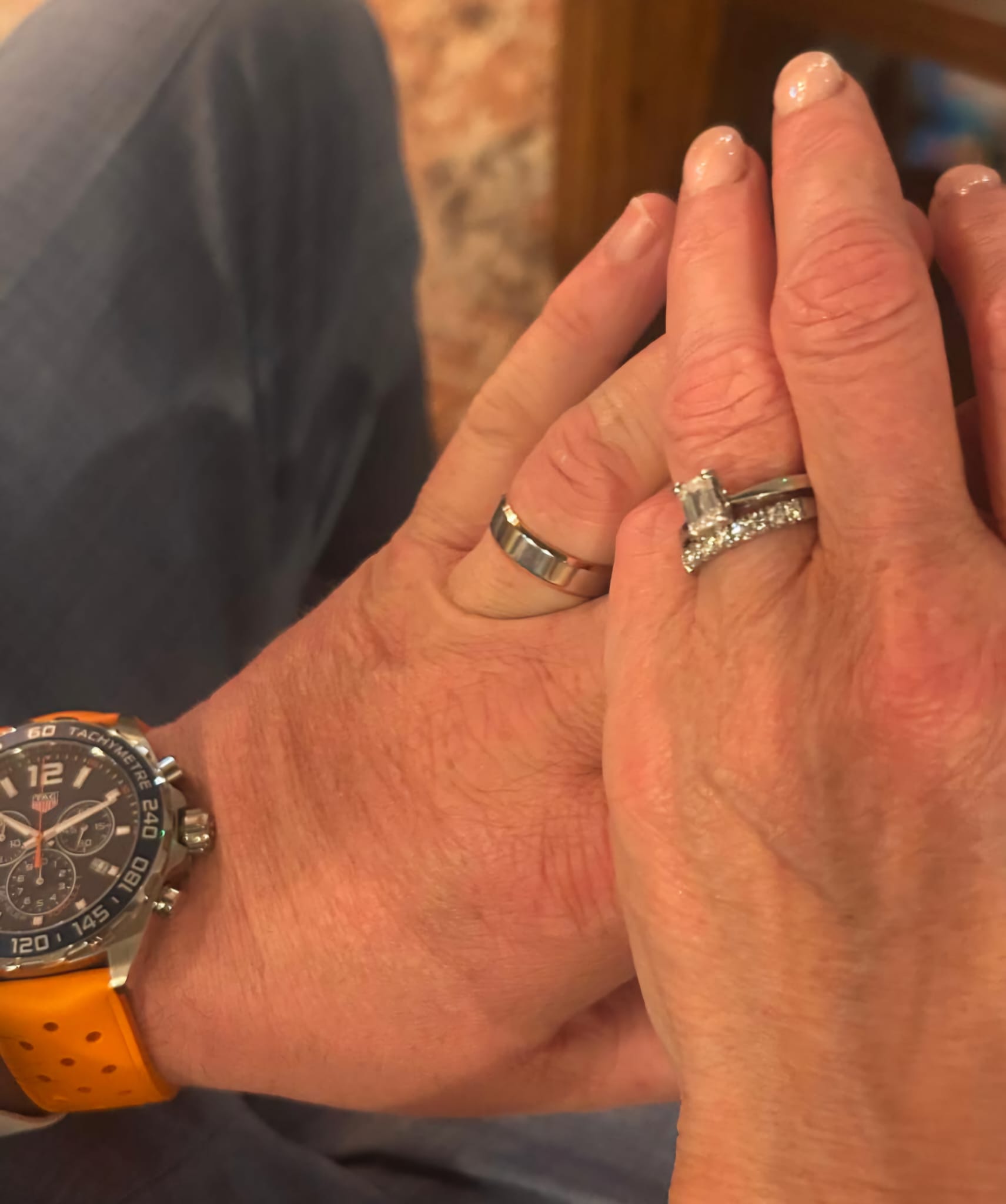 Close-up of two hands with Christine Sadler wedding rings, one wearing an orange watch.