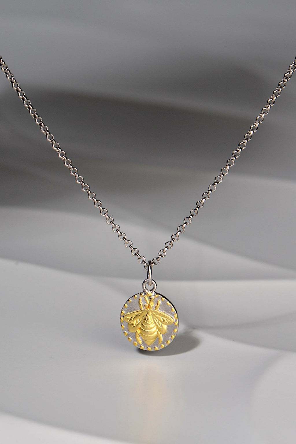 small circular pendant with a gold vermeil bee design on a silver chain - Jorge Revilla jewellery designer