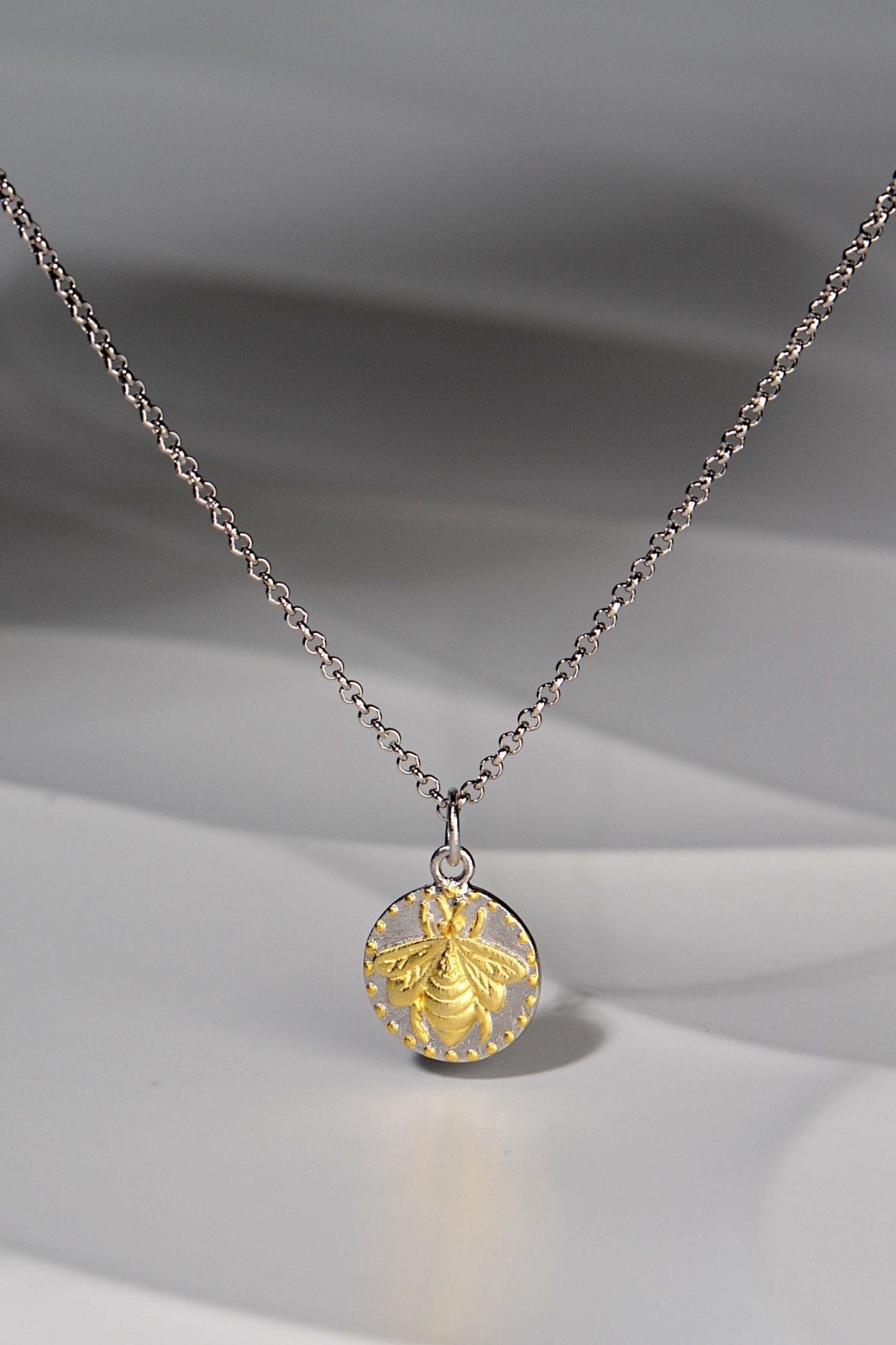 small circular pendant with a gold vermeil bee design on a silver chain - Jorge Revilla jewellery designer