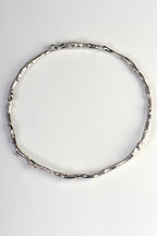 solid round silver handmade bangle in an undulating twig shape that is special and organic by jewellery designer Jorge Revilla