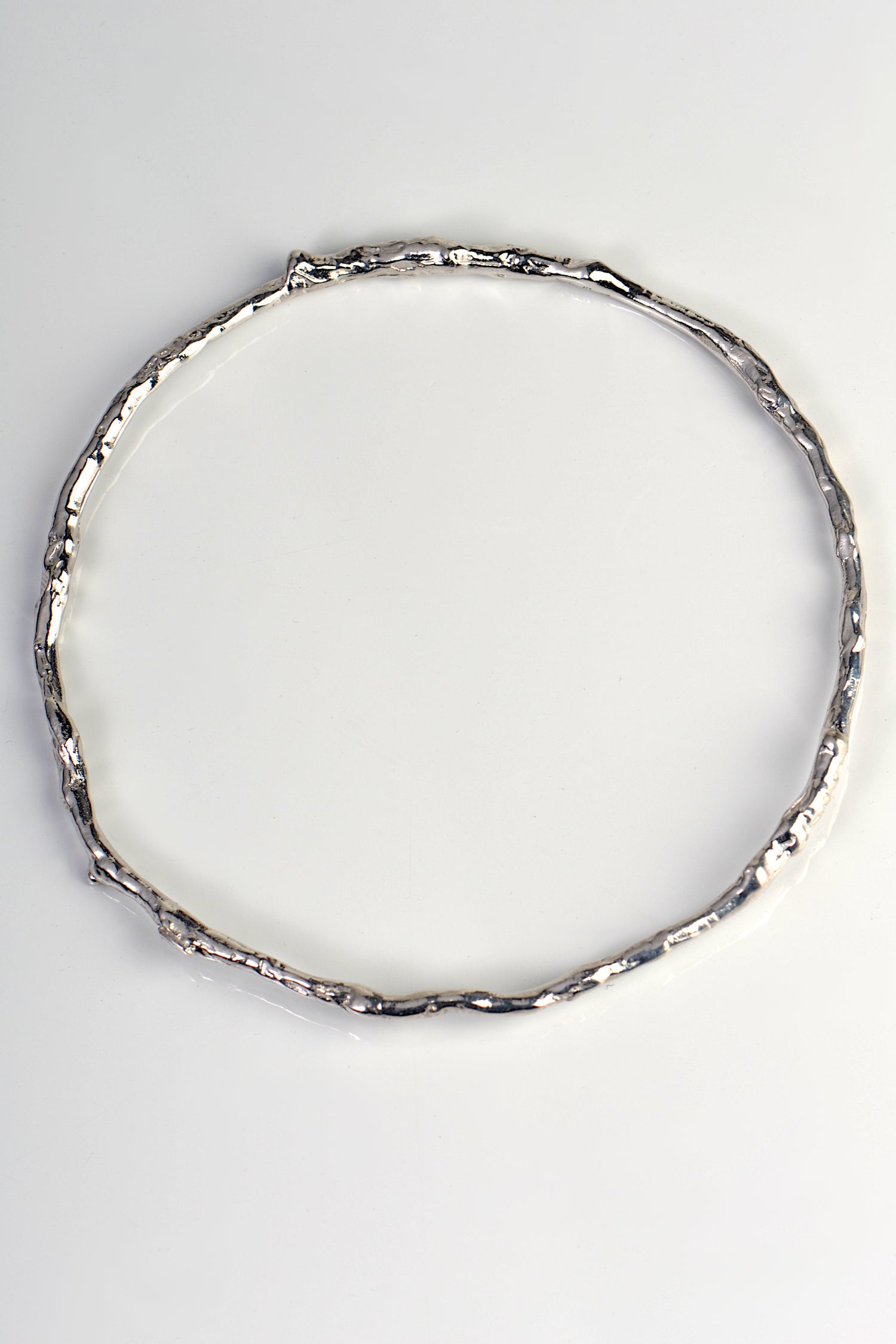 solid round silver handmade bangle in an undulating twig shape that is special and organic by jewellery designer Jorge Revilla