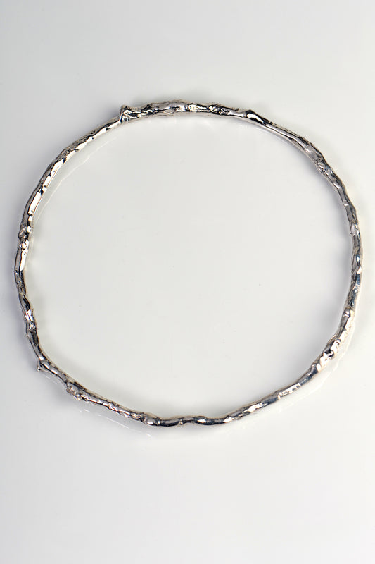 solid round silver handmade bangle in an undulating twig shape that is special and organic by jewellery designer Jorge Revilla