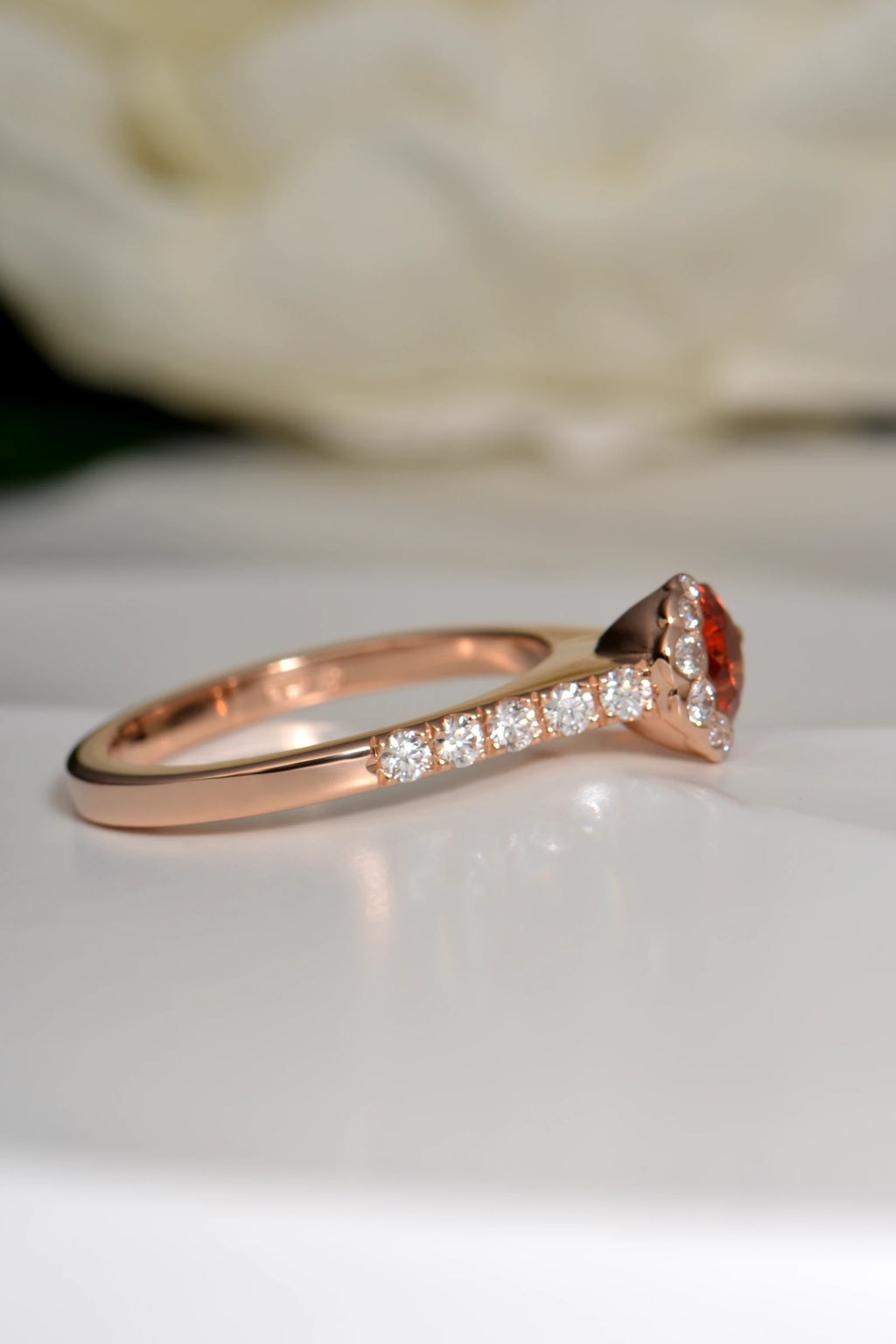 Side view of Fairypools ring in 18ct rose gold, showing orange sapphire and diamond-set shoulders.