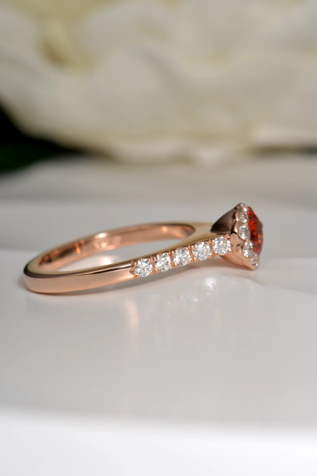 Side view of Fairypools ring in 18ct rose gold, showing orange sapphire and diamond-set shoulders.
