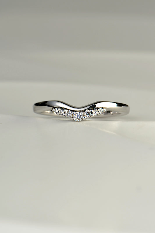 a curved platinum wedding ring in a tiara inspired design with 7 diamonds along the bottom edge of the ring design