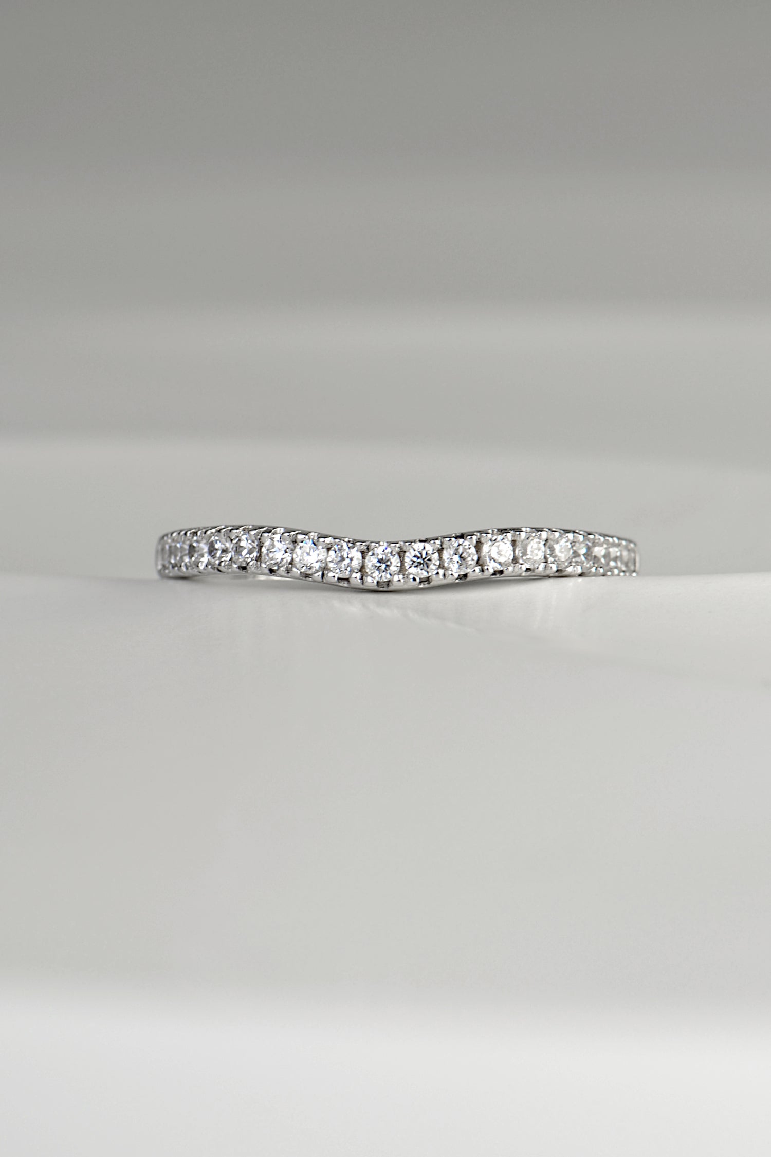 slim platinum wedding ring with a slight curve at the front so that it sits next to an engagement ring that needs a shaped wedding ring.