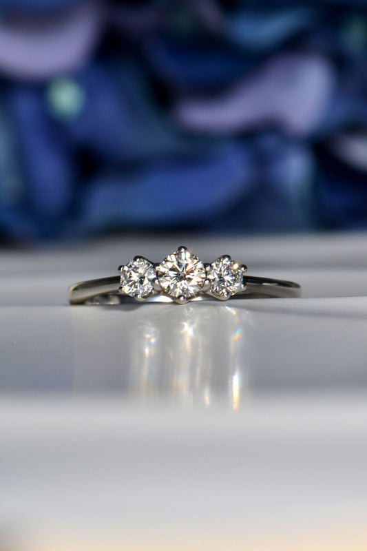 Platinum three stone cathedral diamond engagement ring with round brilliant cut stones in six-claw settings
