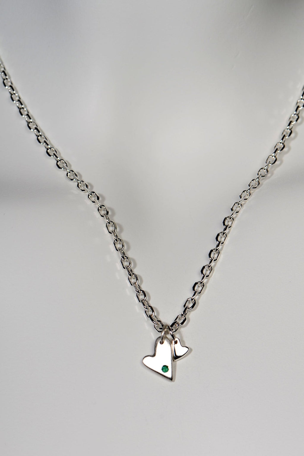 Sterling silver double heart necklace set with emerald displayed on white background from the From The Heart collection by Christine Sadler