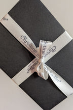 Christine Sadler gift voucher in black envelope with branded ivory ribbon.