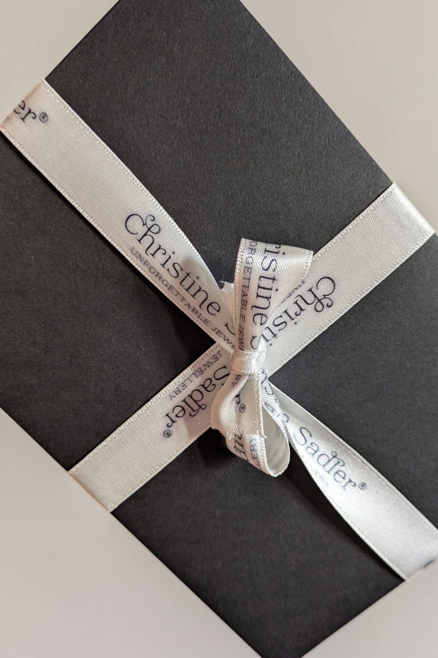 Christine Sadler gift voucher in black envelope with branded ivory ribbon.