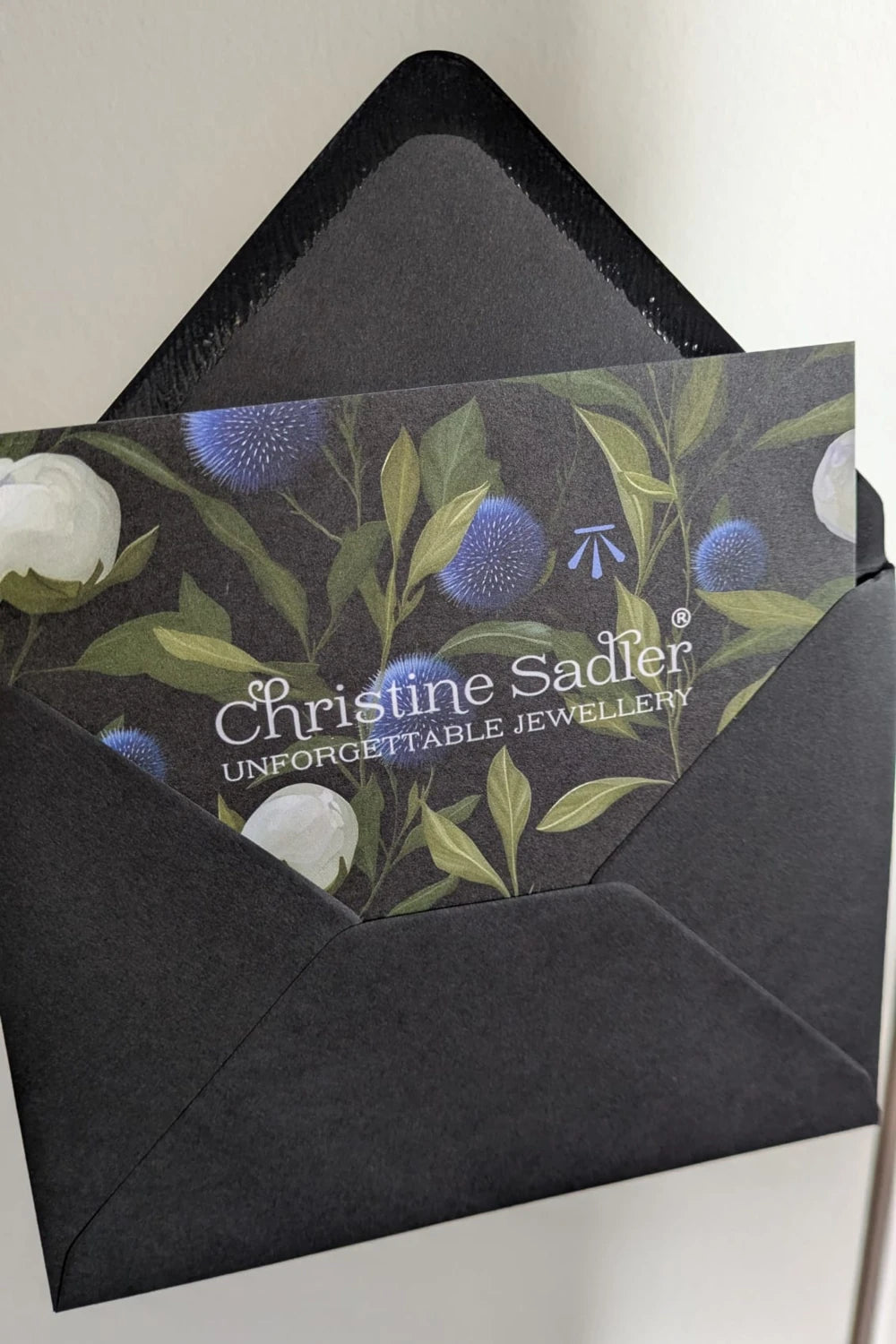 Branded floral card featuring 'Christine Sadler Unforgettable Jewellery' on a neutral background.