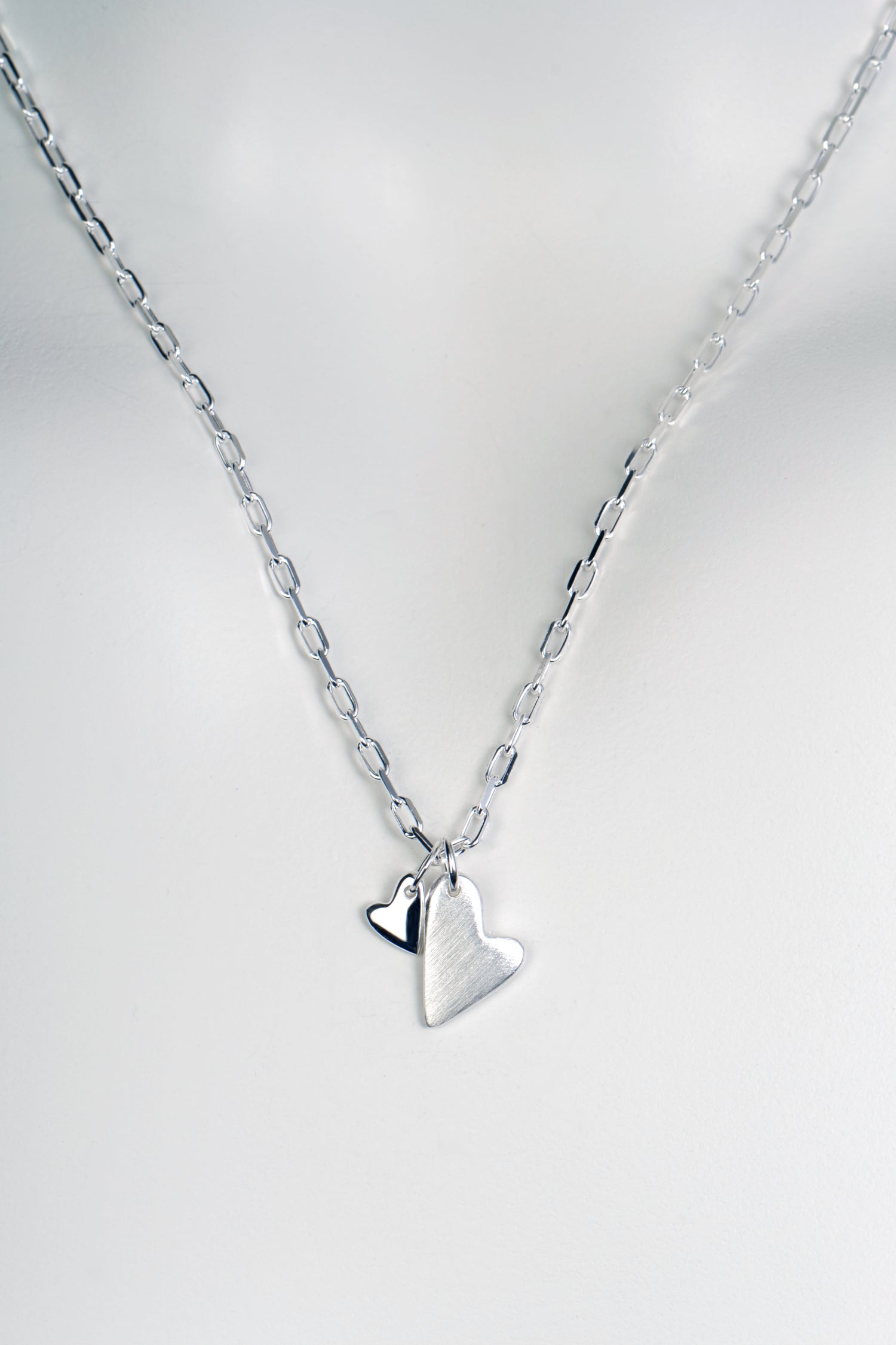 Sterling silver necklace with two heart pendants — one large matt heart and one small polished heart, From The Heart collection on white background