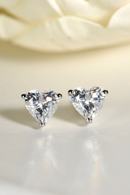 sparkly cz heart earrings in rhodium plated silver with blurred cream flowers in the background 