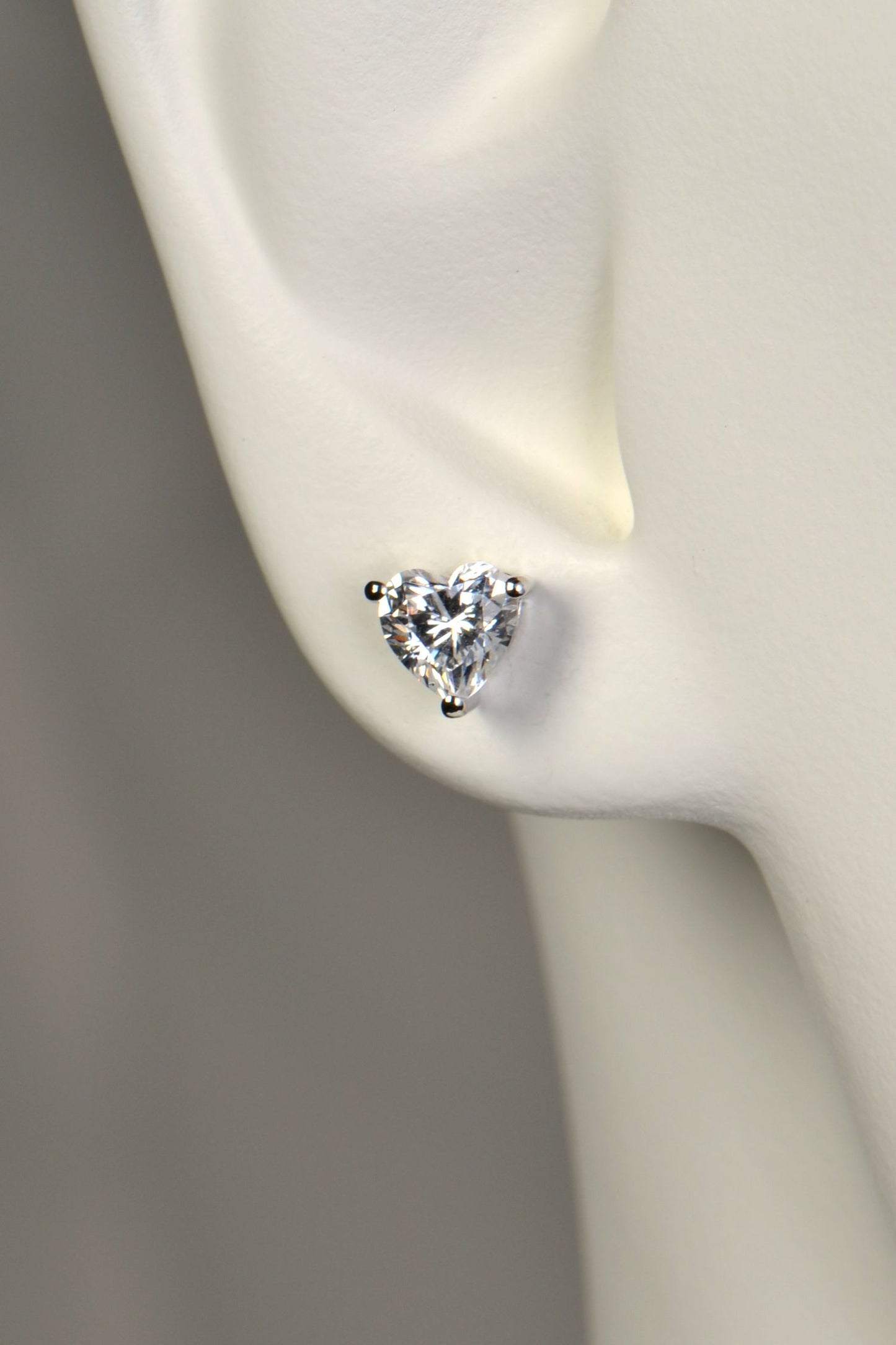 Heart-shaped sparkling earring on a mannequin ear