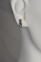 oxidised silver earring in model's ear. It sits on the ear lobe and extends just below it. There is a diamond at the bottom of the rectangular earring.  These designer earrings are by Christine Sadler and are called Hero