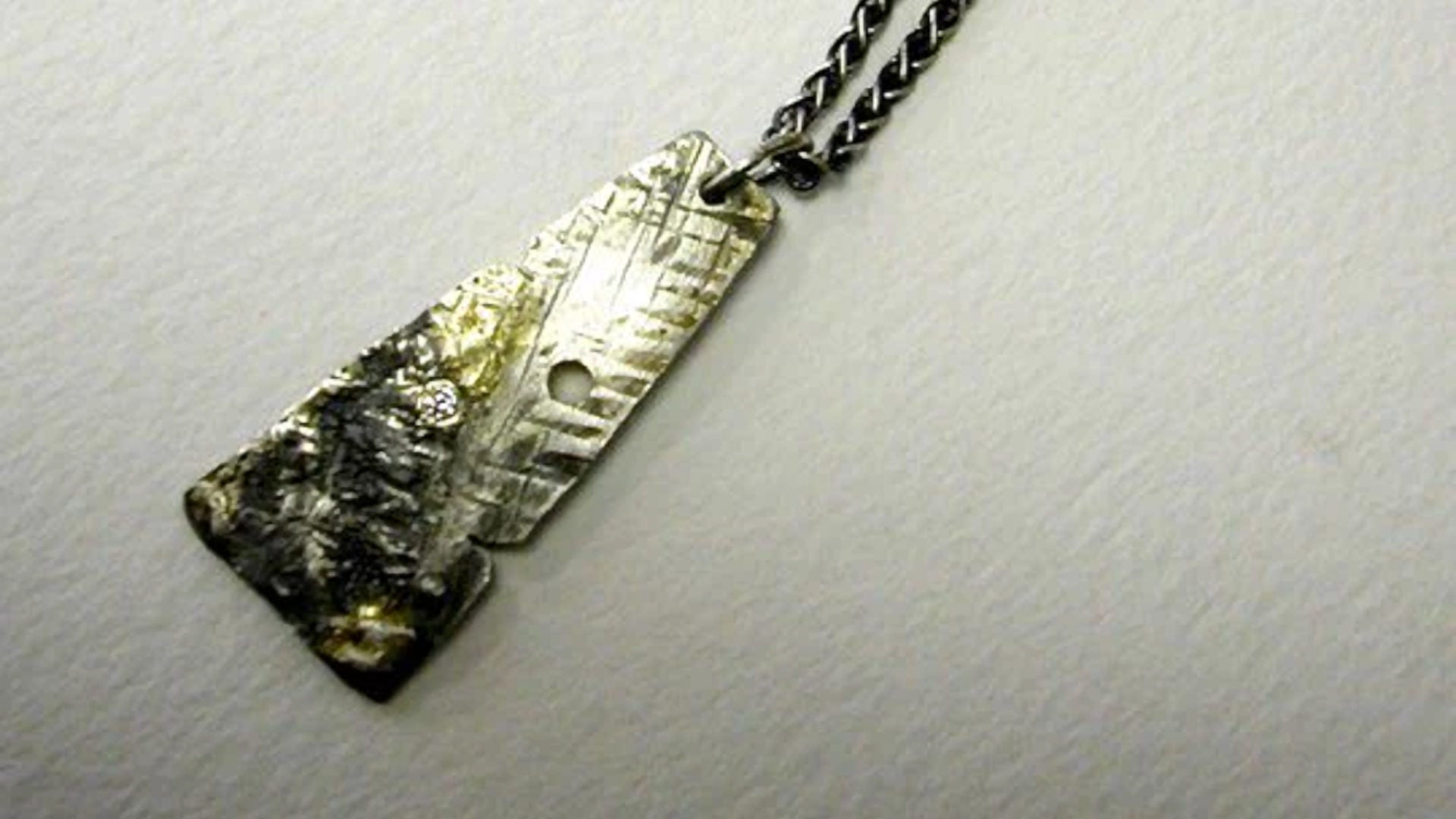 one-of-a-kind textured oxidised silver pendant set with a diamond from Christine Sadler's Hero collection on a white art paper background