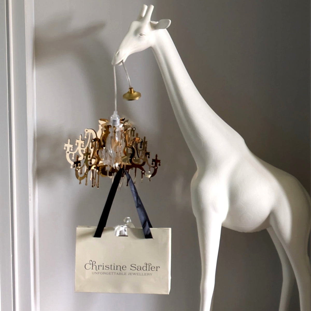 Picture of a Qeeboo giraffe in love holding a Christine Sadler jewellery gift bag to she her beautiful free designer jewellery gift wrapping in her jewellery studio in Ayr