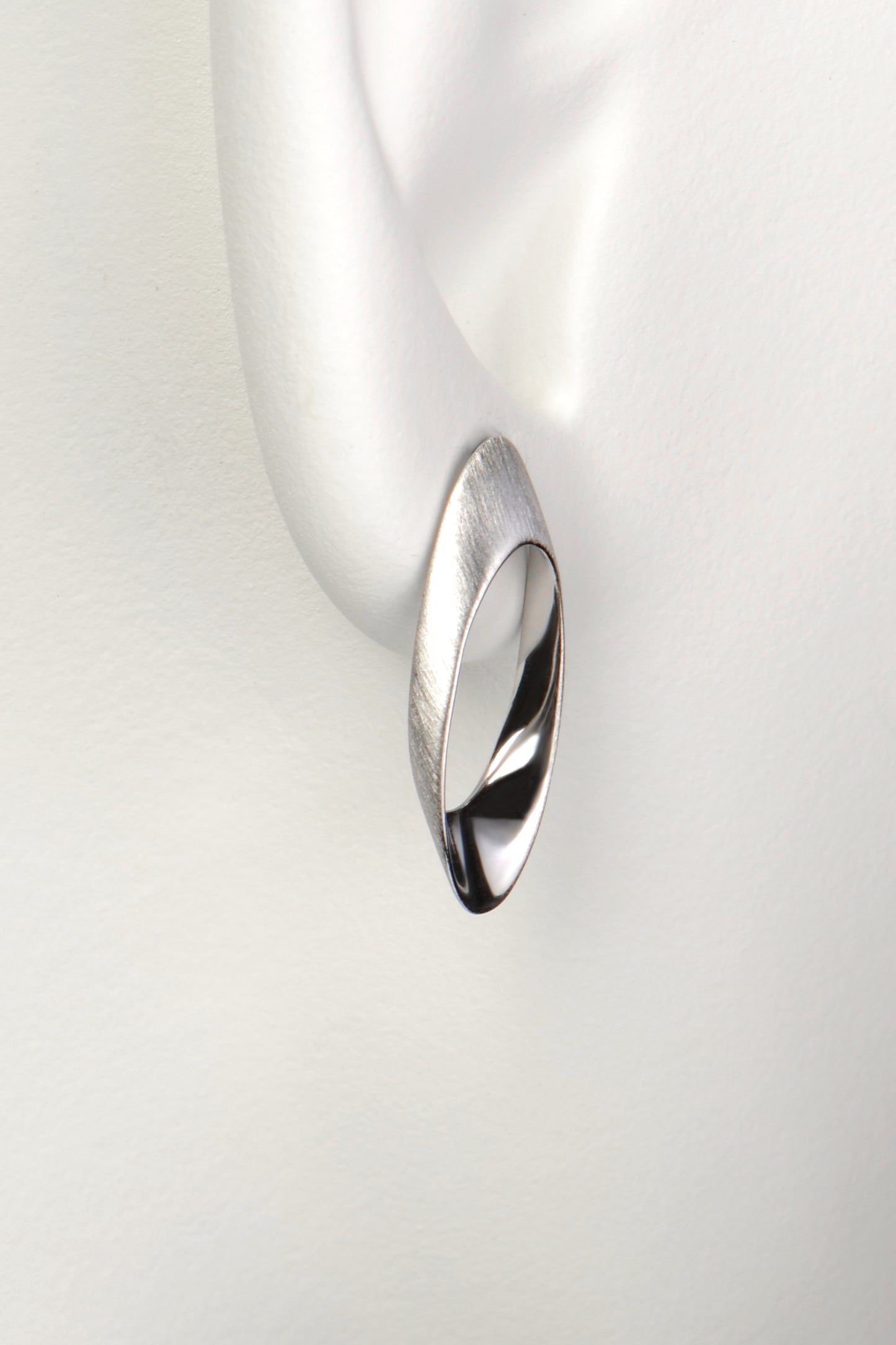 long oval designer silver stud earring that sits on the lobe and drops down below it. 