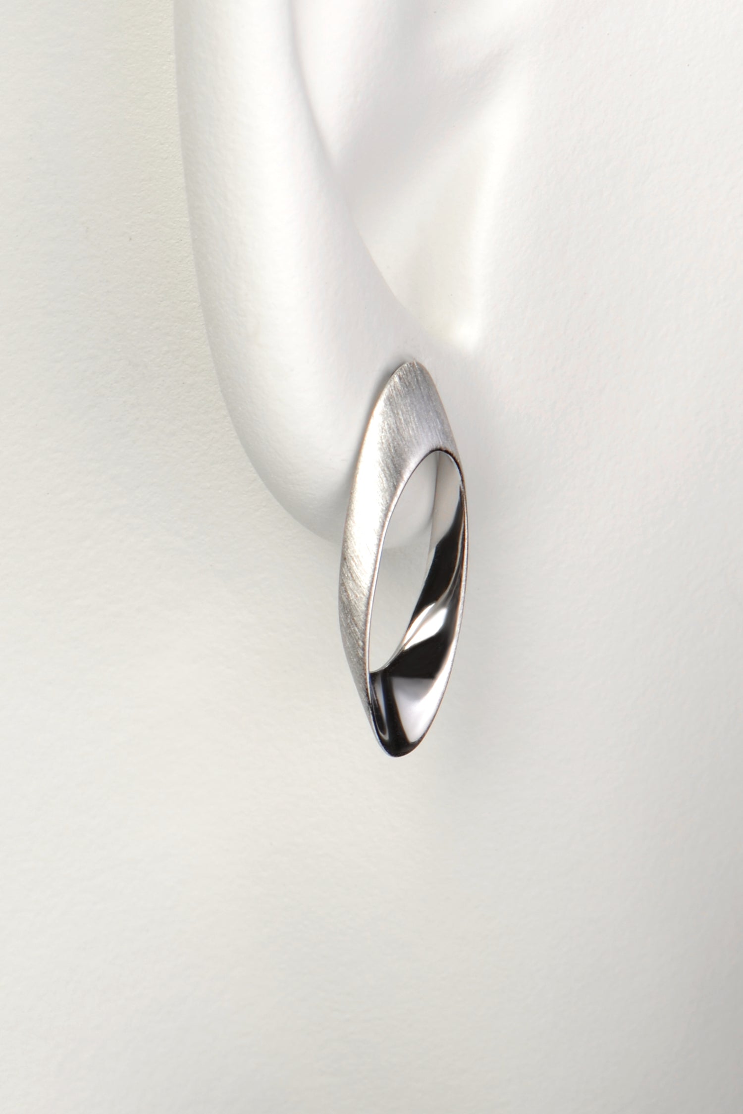 long oval designer silver stud earring that sits on the lobe and drops down below it. 
