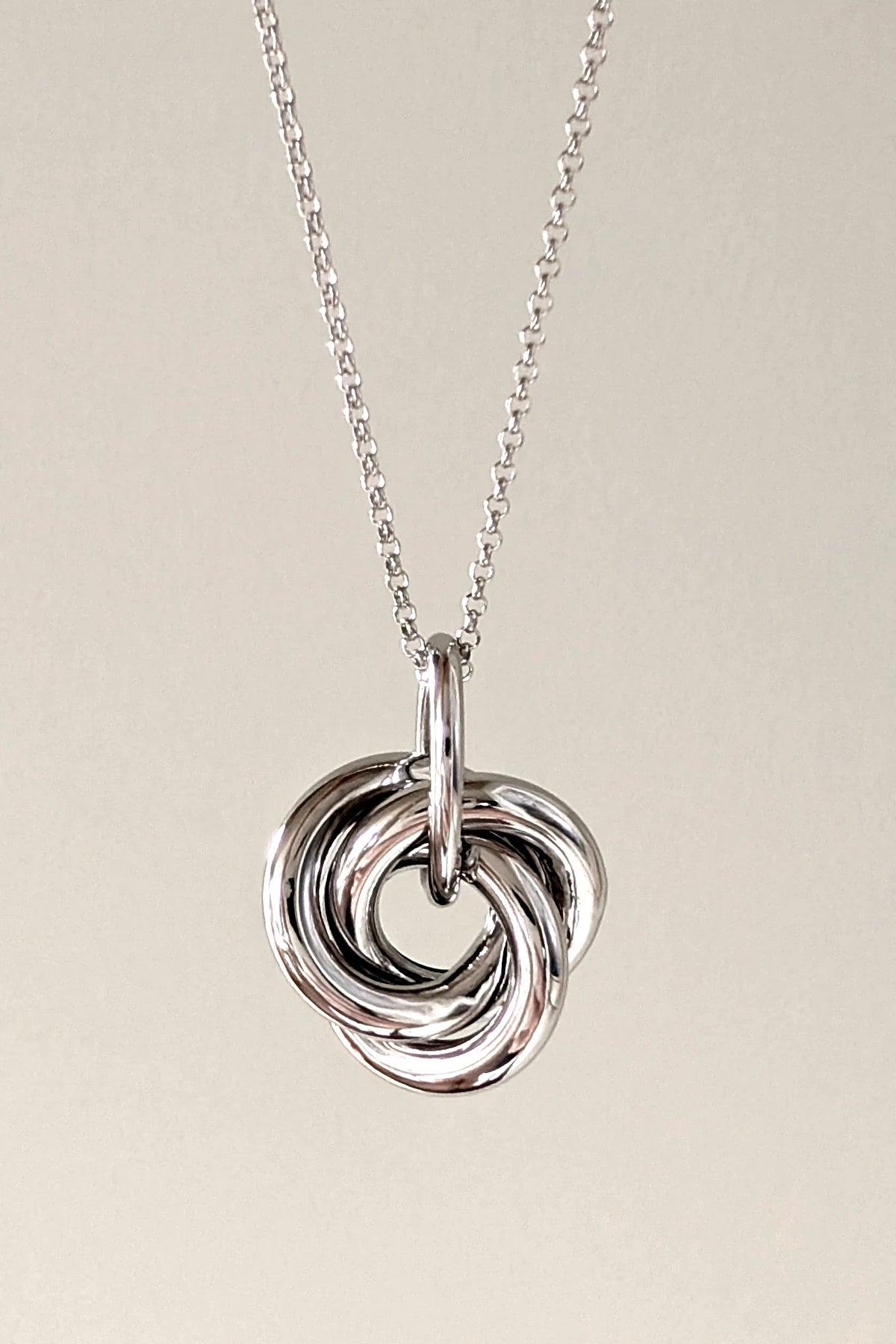Large sterling silver knot pendant hanging from a silver chain.