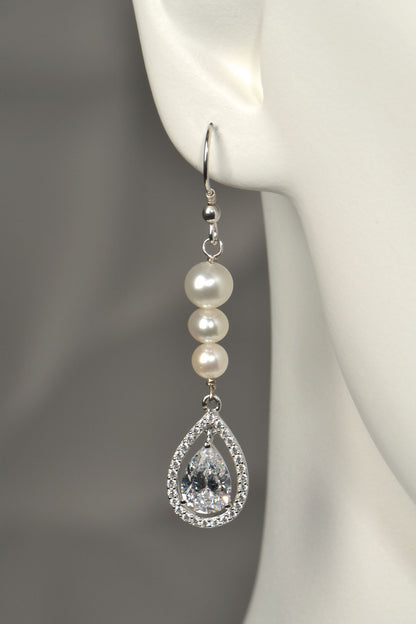 Close-up of graduated pearl drop earring with pear-cut cubic zirconia halo pendant in silver on white mannequin to show the size and scale
