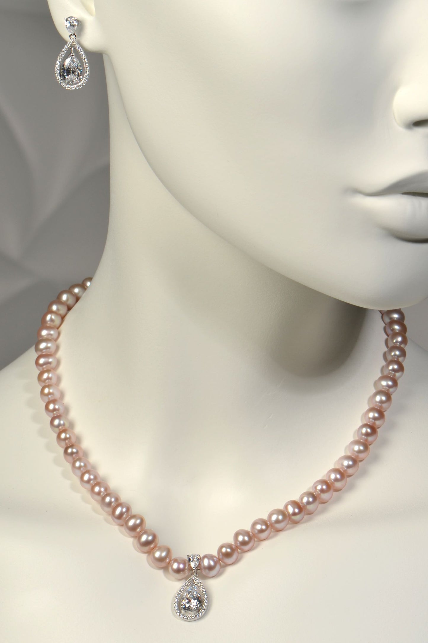 Mannequin wearing a pink pearl necklace with matching earrings on a neutral background