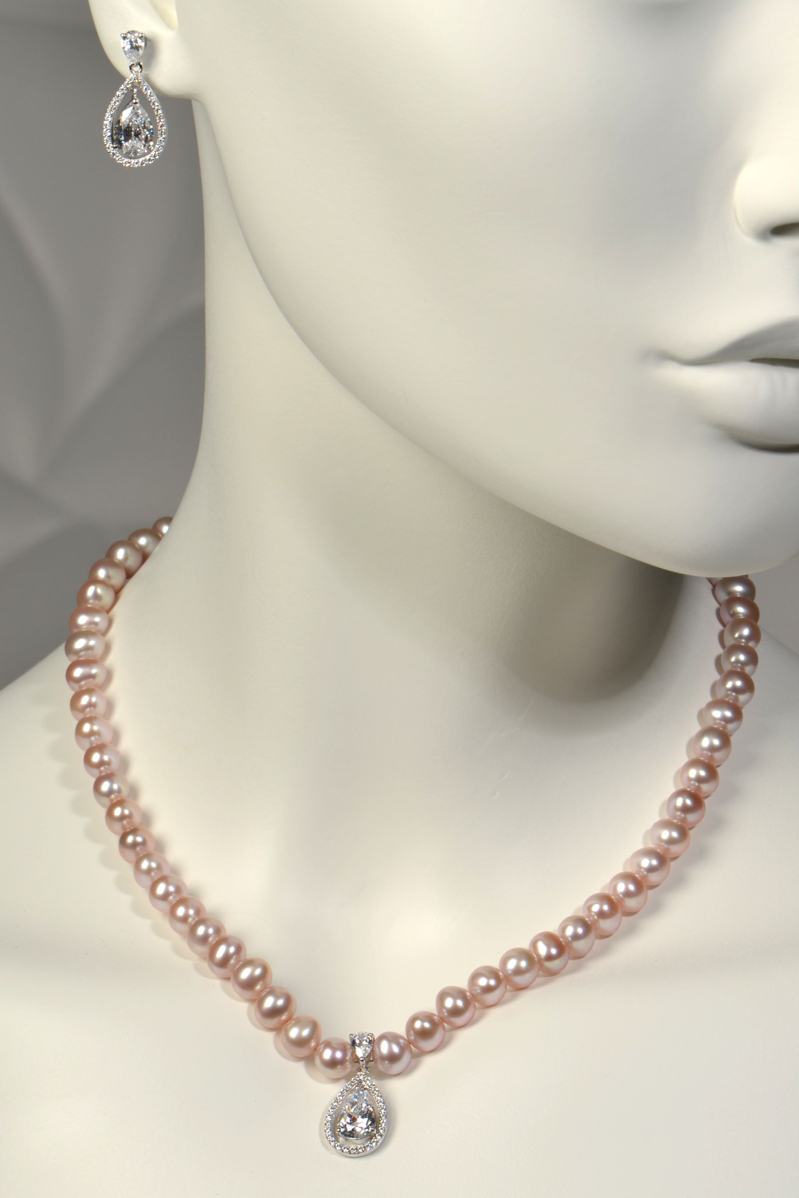 Mannequin wearing a pink pearl necklace with matching earrings on a neutral background