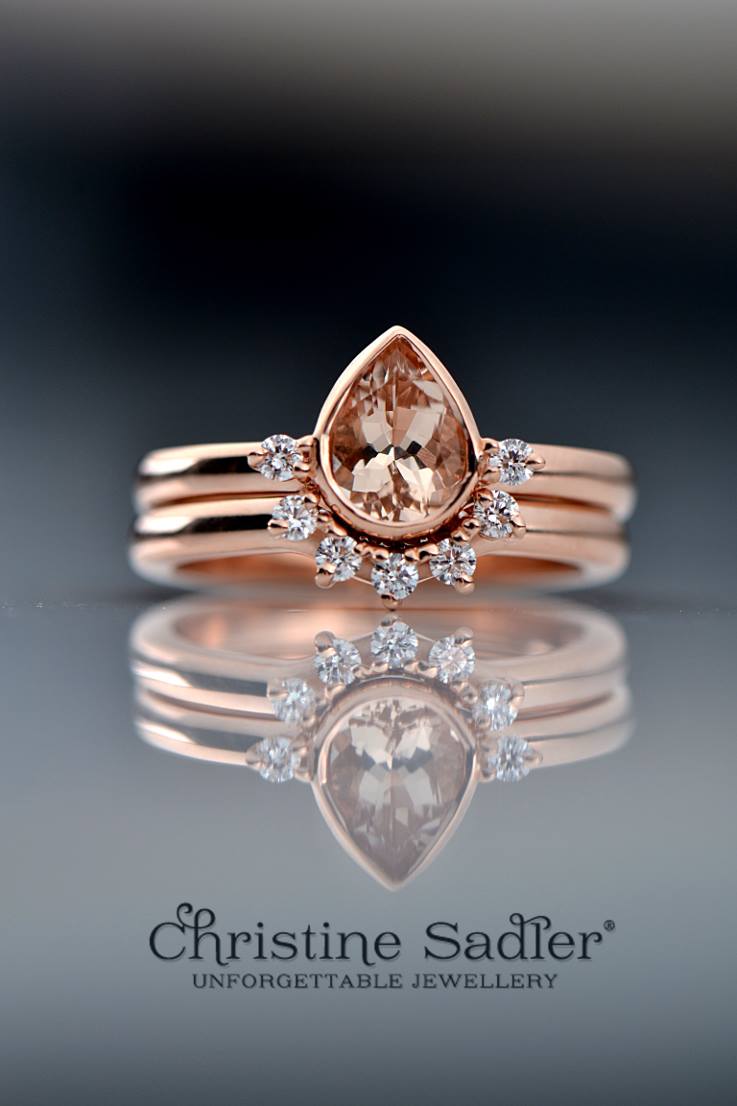 matching engagement ring and wedding ring that fit together in rose gold and diamond with a pear cut morganite