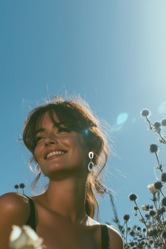 woman wearing large silver statement drop earrings from the natural beauty collection with blue sky background