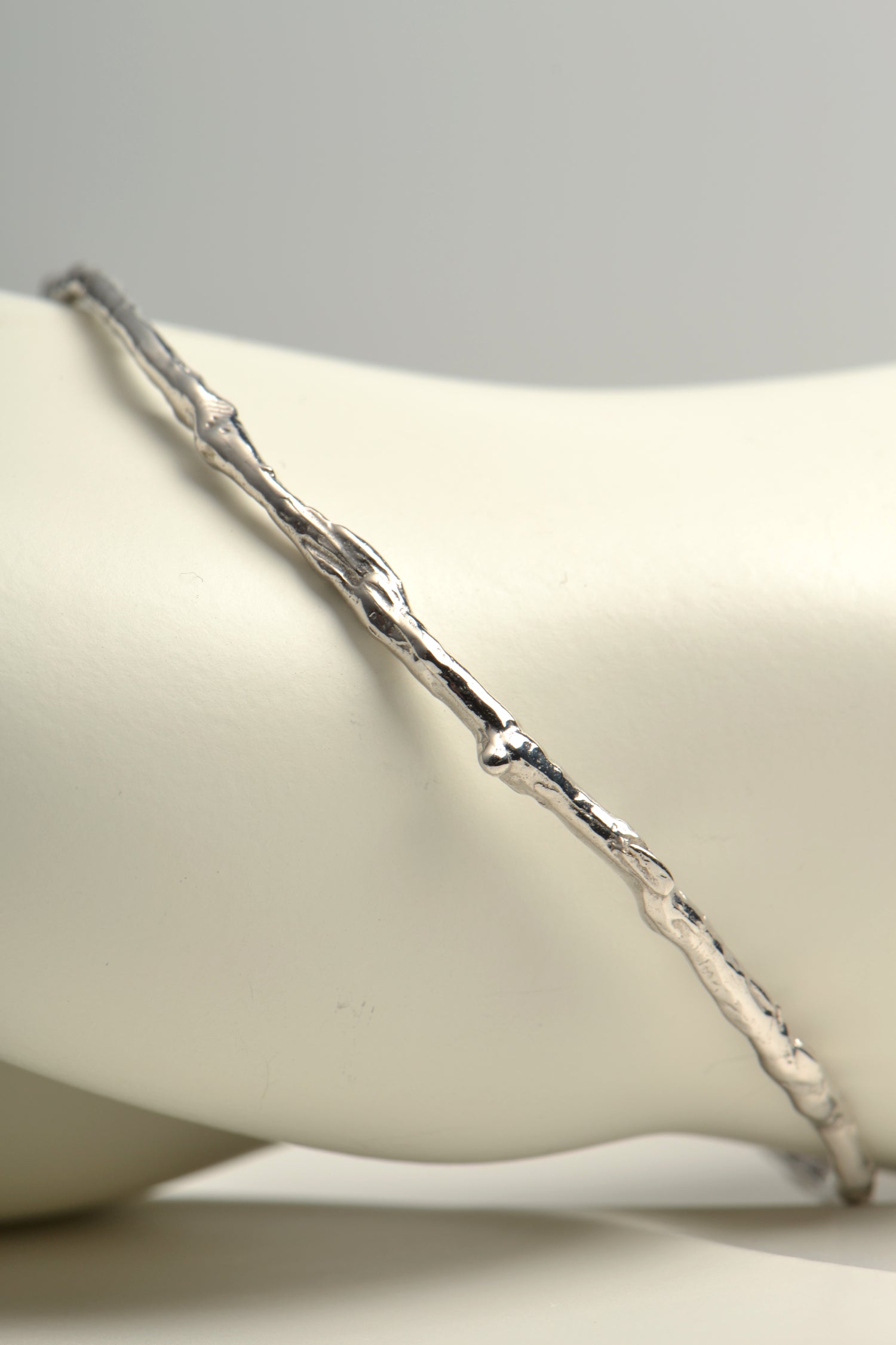 silver organic shaped round bangle that looks like it is made from a twig by jewellery designer Jorge Revilla
