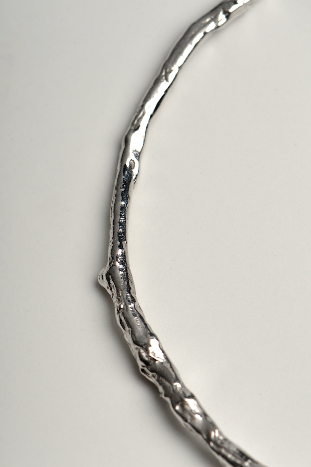close up details of silver bangle that looks like a twig, a nature inspired design by Jorge Revilla