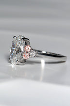Close-up of Rosé Spark ring showing two pink lab diamonds and one white lab diamond on each side of the central oval stone, forming a white–pink–white sequence.