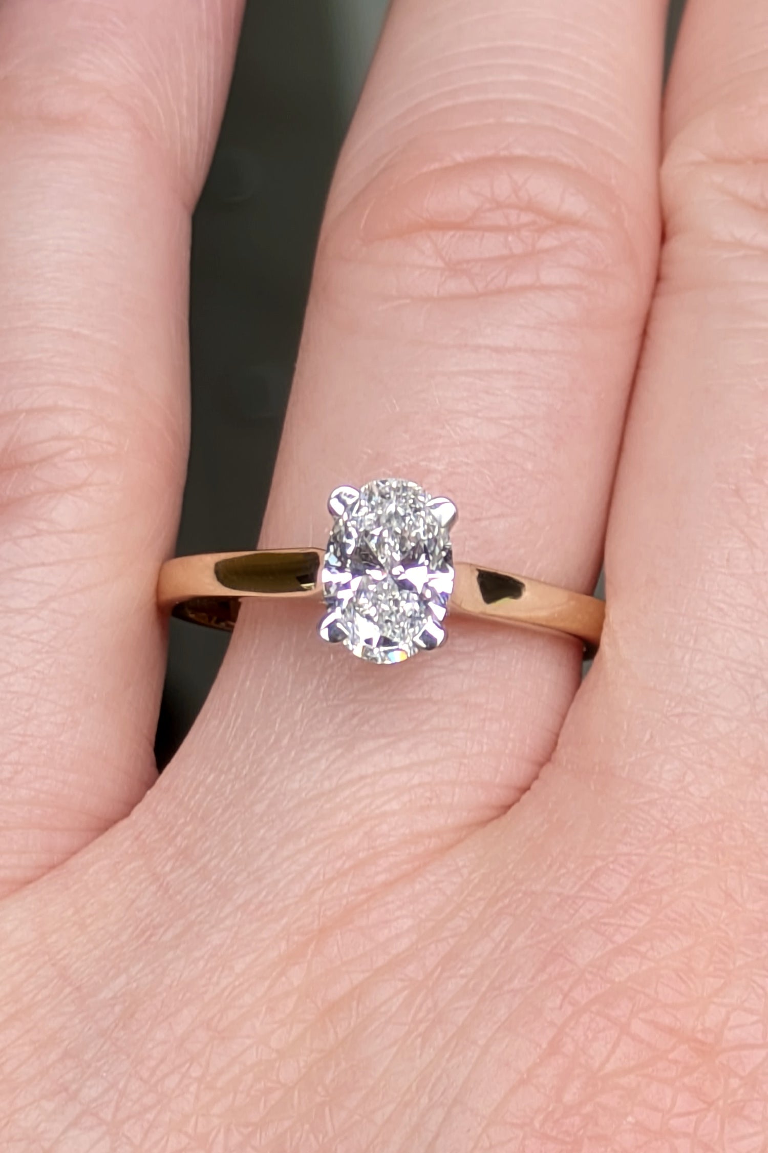 Oval cut lab diamond ring in 18ct yellow gold and platinum shown on a finger to show scale and style. This two tone engagement ring is handmade in the UK.