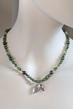 silver seed pod pendant on unique green and black pearl necklace