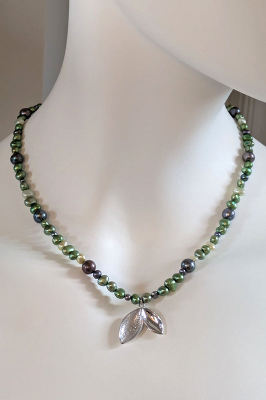silver seed pod pendant on unique green and black pearl necklace