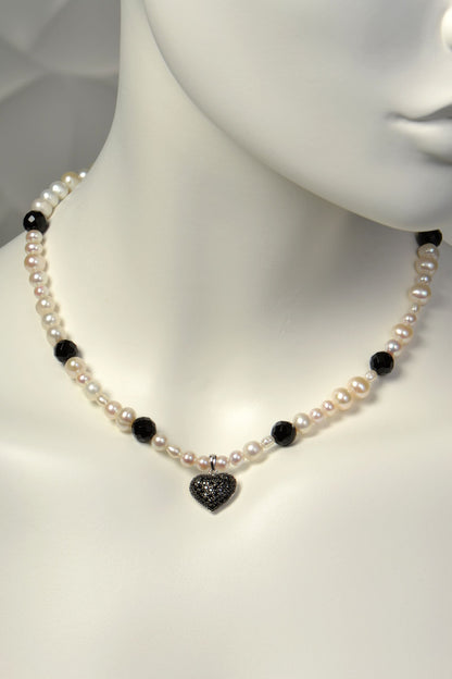 Cultured pearl necklace with black heart pendant and onyx gemstones on a mannequin