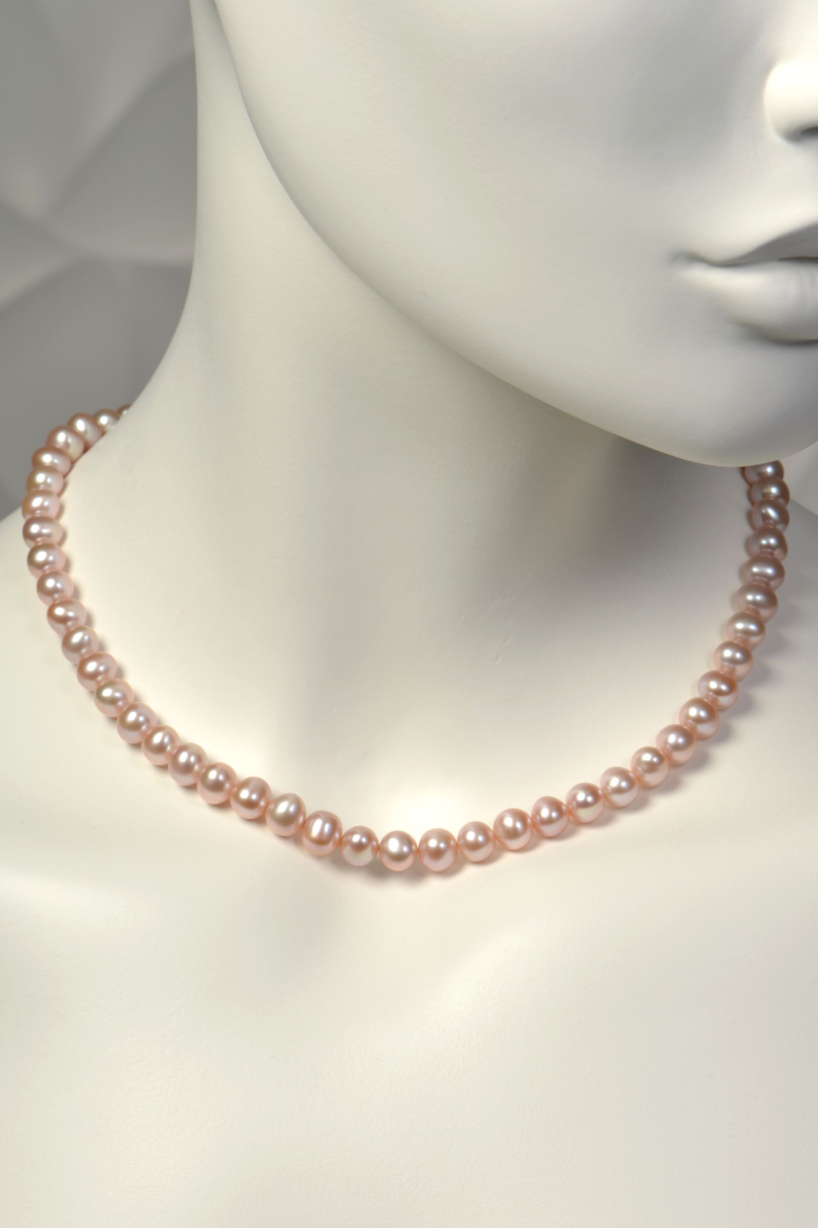 Pink cultured pearl necklace on a mannequin head against a white background