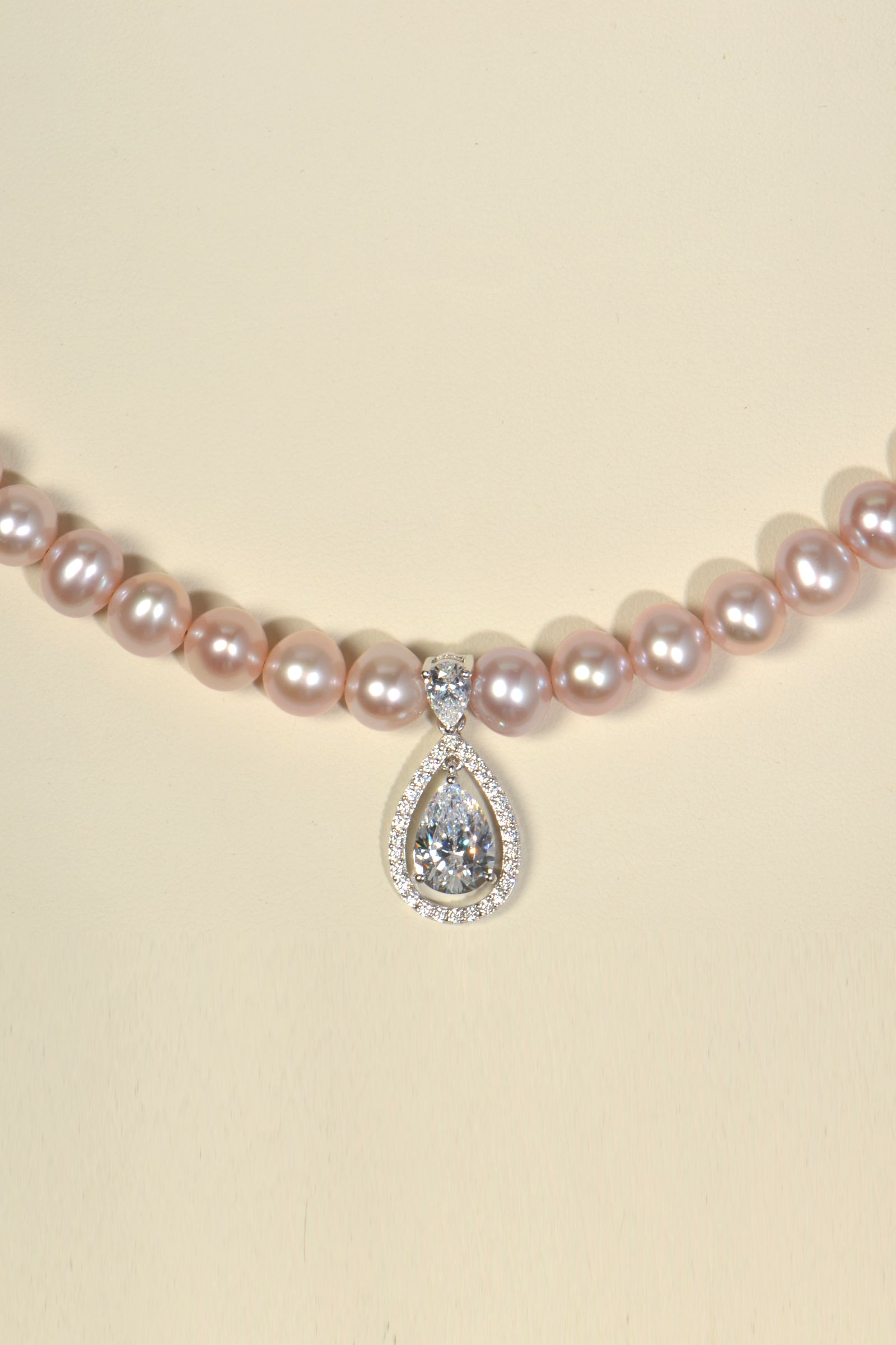 close up detail of pear cut halo pendant at the front of pink pearl necklace