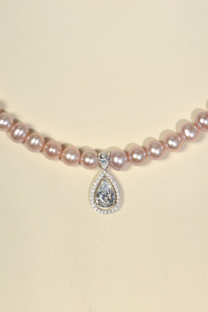 close up detail of pear cut halo pendant at the front of pink pearl necklace