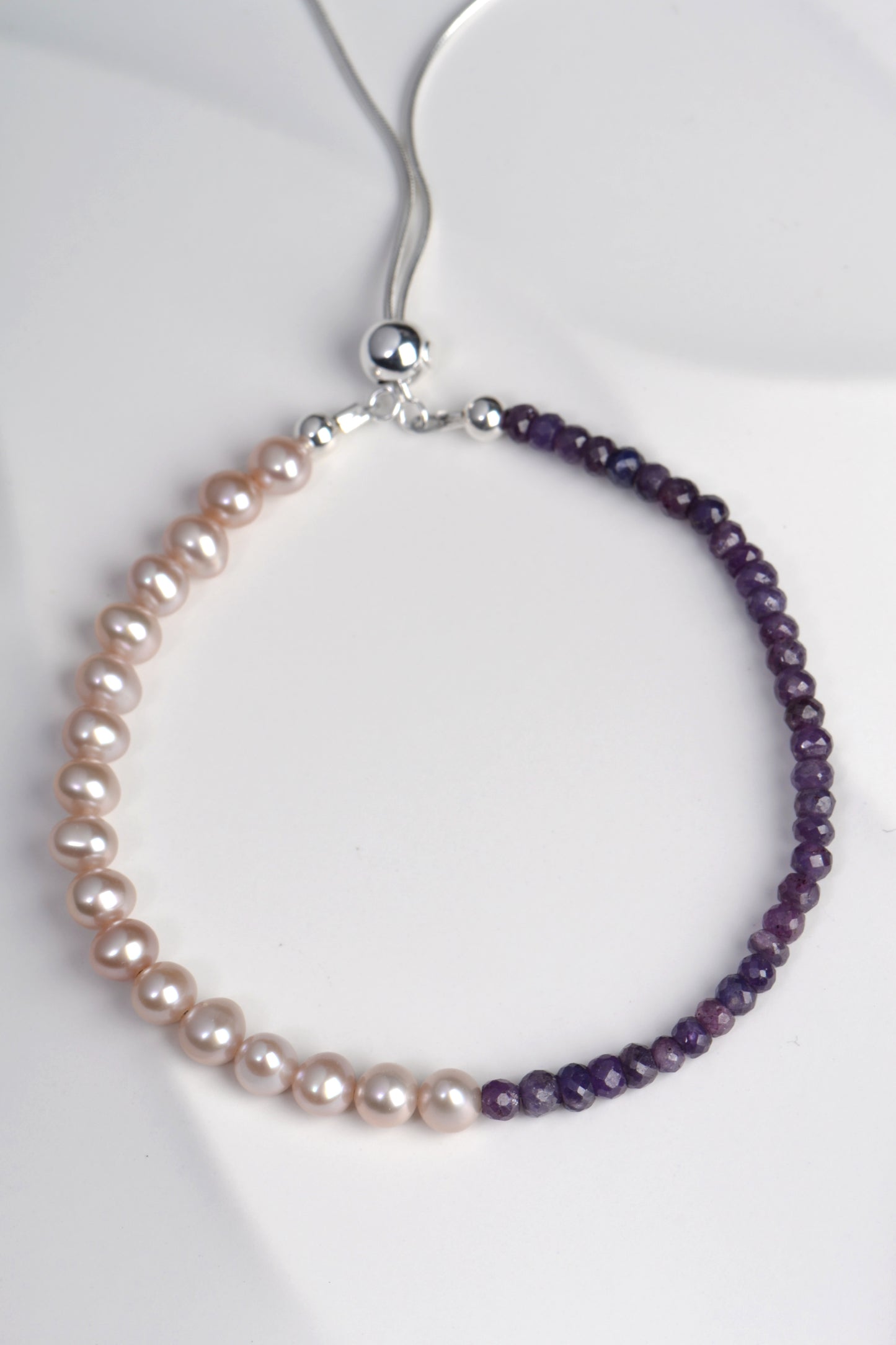 designer bracelet with half pale pink pearls and half purple sapphires with silver adjustable clasp