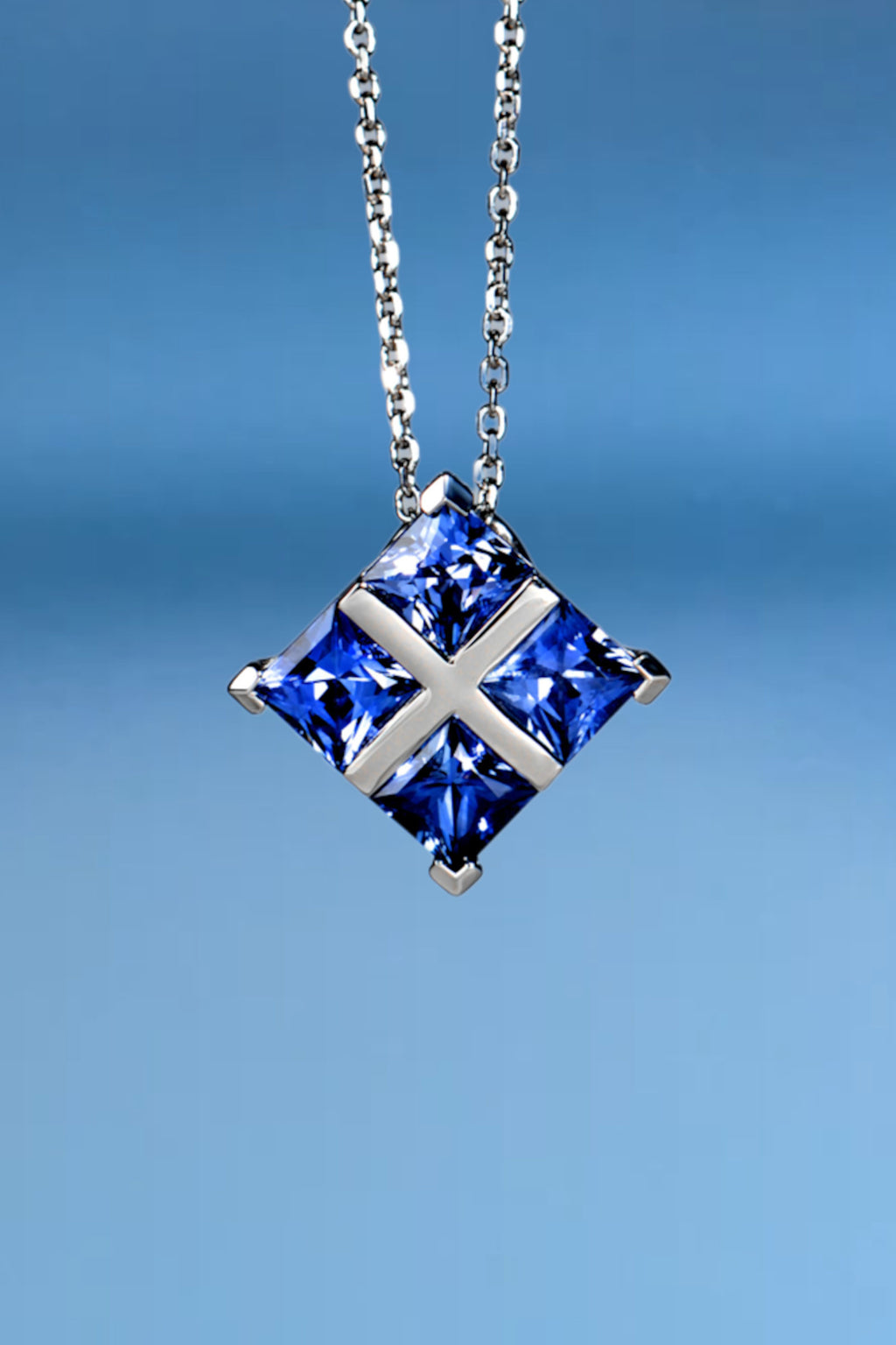 Luxury tartan-patterned platinum pendant necklace featuring four princess-cut blue sapphires.