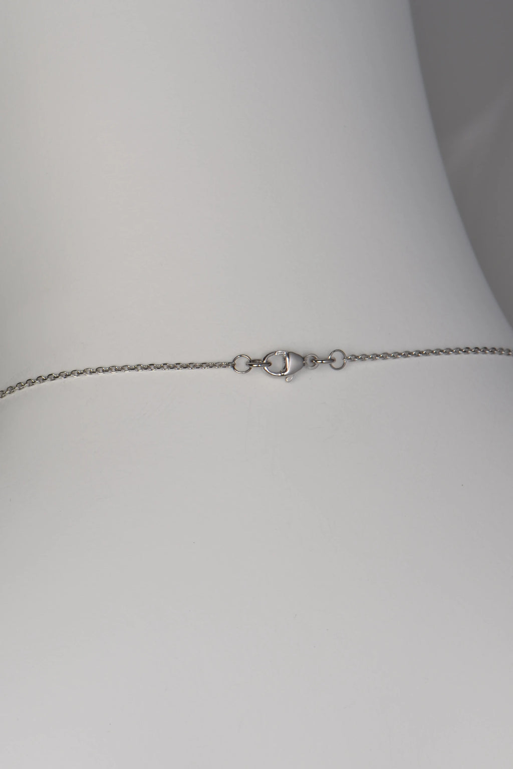 A polished platinum lobster claw clasp securing a delicate, flat-edged filed trace chain on a Tartan collection necklace.