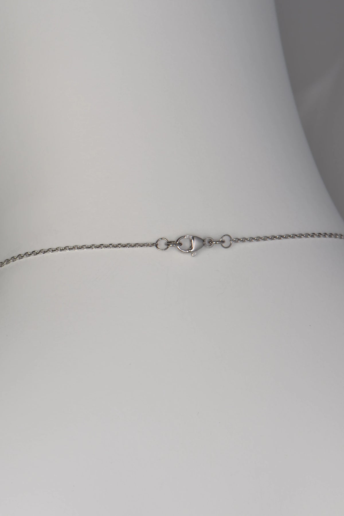 A polished platinum lobster claw clasp securing a delicate, flat-edged filed trace chain on a Tartan collection necklace.
