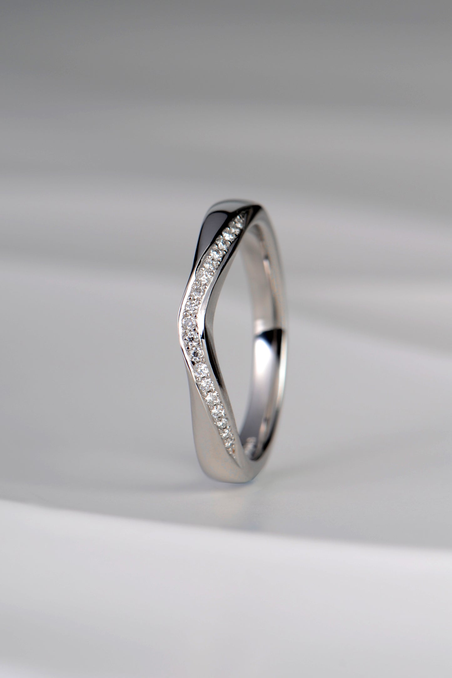 U shaped platinum diamond set wedding ring that is special and different as it has a ribbon of diamonds on the curved edge