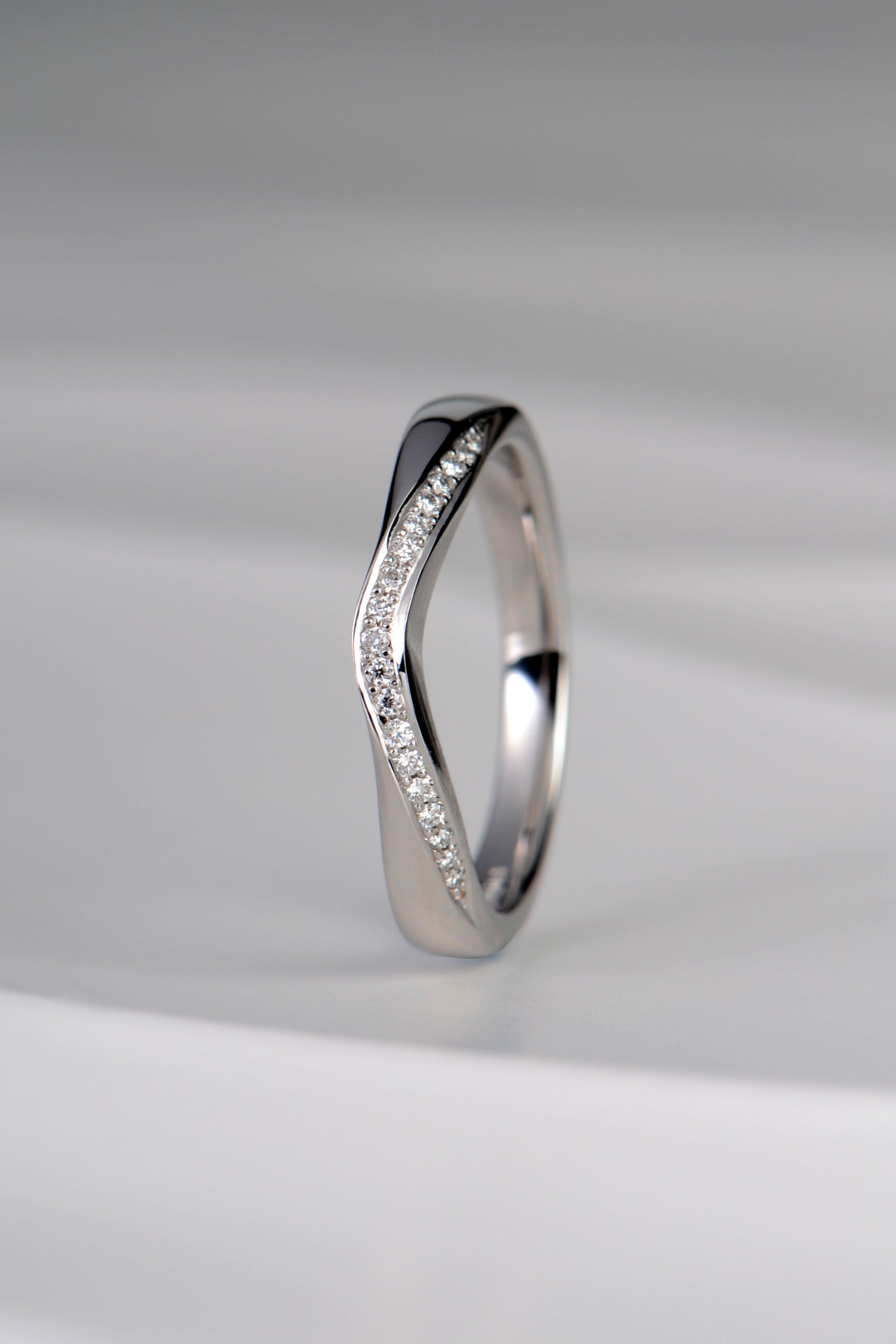 U shaped platinum diamond set wedding ring that is special and different as it has a ribbon of diamonds on the curved edge