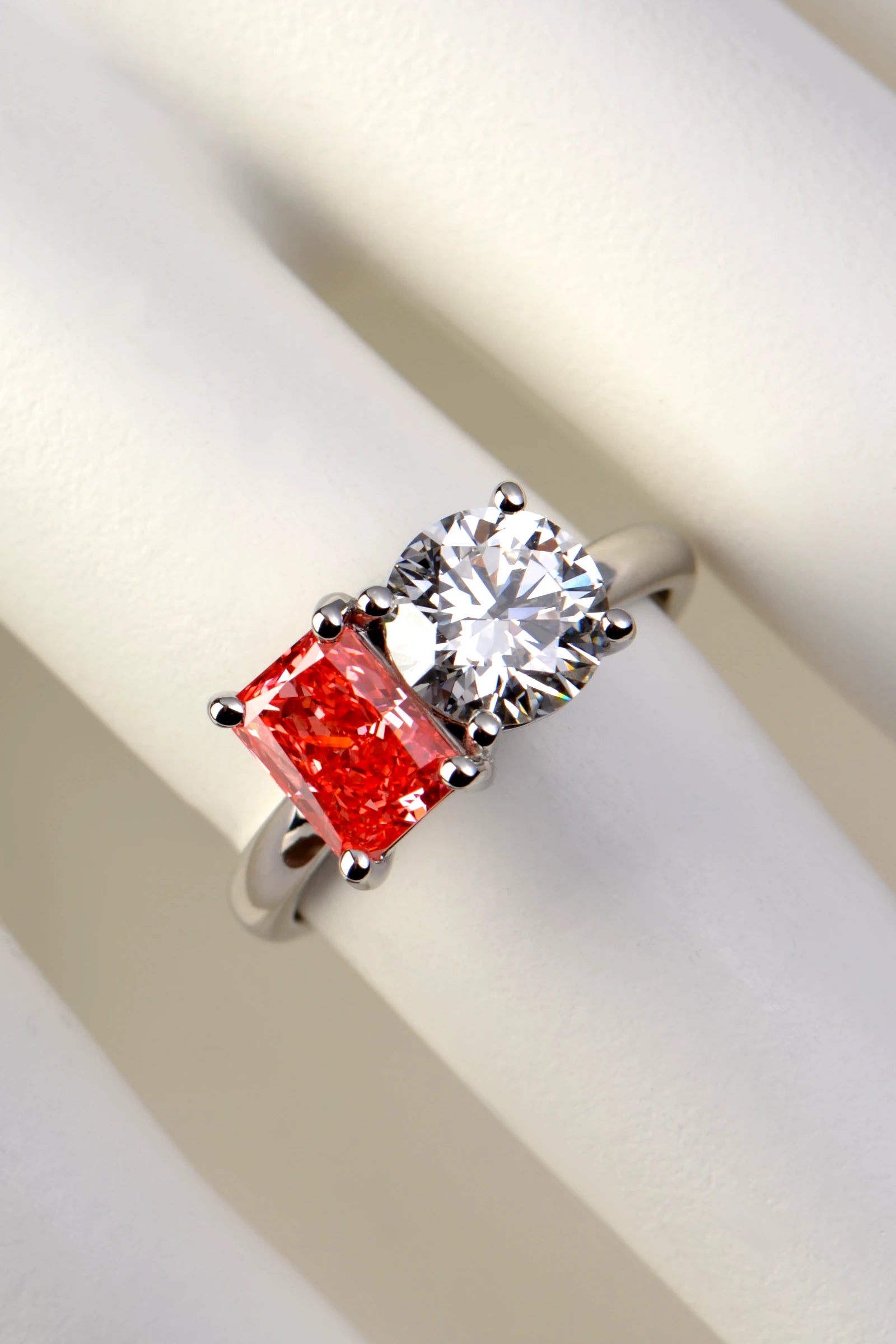 A 1.29 carat pink and 1.58 carat white diamond Moi et Toi platinum ring displayed on a white mannequin hand to show finger scale, by Christine Sadler